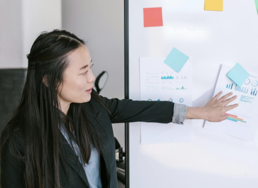 Asian Woman Holding Notes Against a Whiteboard